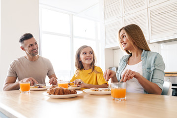 Photo of happy family smiling and talking while having breakfast