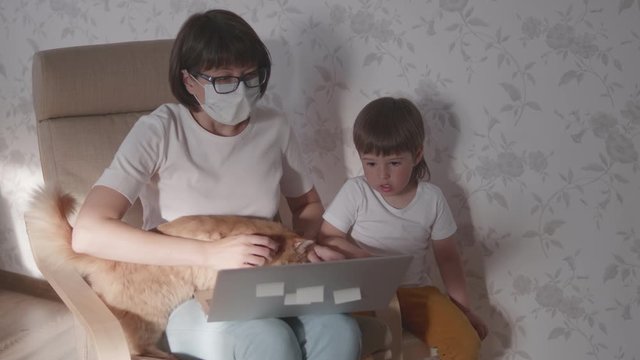 Mother, toddler son and cat sit together on chair with laptop. Woman tries to remote work, but kid is asking for game or cartoons. quarantine lockdown because of coronavirus COVID-19. 10bit V-logL