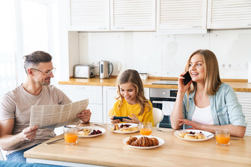 Photo of family using smartphones while having breakfast