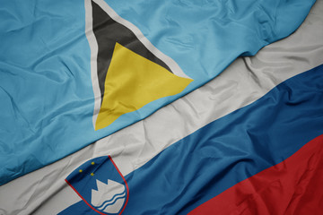 waving colorful flag of slovenia and national flag of saint lucia.