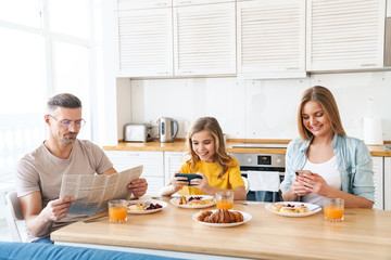 Photo of family using smartphones while having breakfast