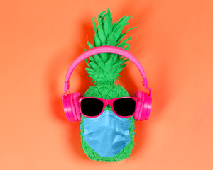 Pineapple in pink headphones and glasses on a orange background