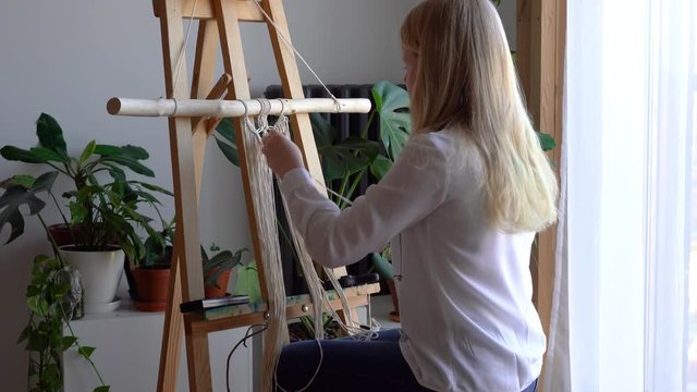 stay at home. work during the quarantine - a girl in the living room mural weaving of the ropes in the macrame technique