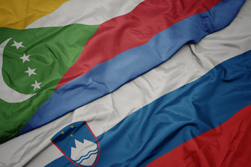 waving colorful flag of slovenia and national flag of comoros.