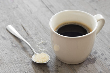 Coffee cup with sugar on metal spoon.