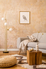 Obraz na płótnie Canvas Modern concept of living room interior with gold lamp, design grey sofa, wooden cube, rattan pouf, mock up picture frame, dried flowers in vase, carpet and elegant accessories in home decor.