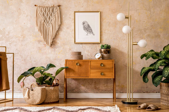 Modern retro composition of living room with wooden vintage commode, furniture, lamp, plant, carpet, pillows, gold mock up poster frame, plants, decoration and personal accessories.