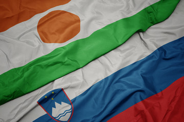 waving colorful flag of slovenia and national flag of niger.