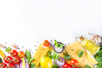 Italian food ingredients for  cooking Spaghetti Pasta. Raw spaghetti pasta with various ingredient - onion, tomatoes, garlic, basil, parsley, cheese, olive oil. On white table background, flatlay copy