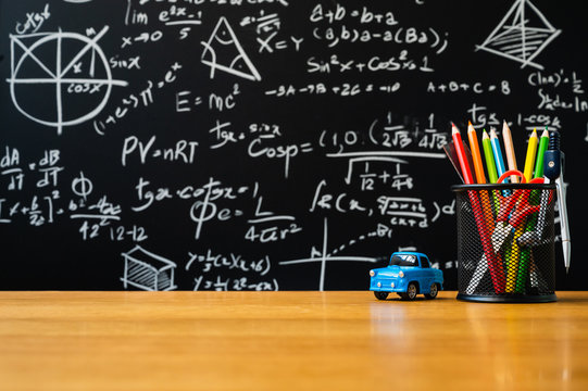 Education background concept. Stationery in holder color pencil, compasses tool, scissors, rulers, car toy On chalkboard with the Mathematical formula background.