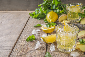 Homemade ginger lemonade cocktail. Cold summer ginger lemon ale. Sweet and sour iced refreshing beverage with lemon slice garnish,  Detox and weight loss drink concept. Wooden rustic background copy s