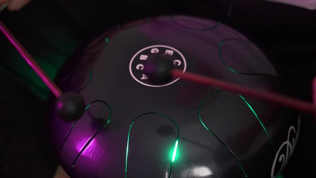 a man sits at home and plays on the hapi drum