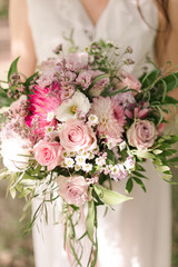An unusual bride's bouquet. The bride is holding the bouquet in her hands.  