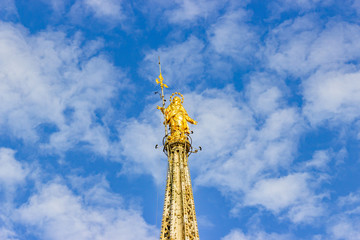 Fototapeta premium The gilded statue on the roof of Cathedral of Milan - Duomo di Milano in Milan, Italy