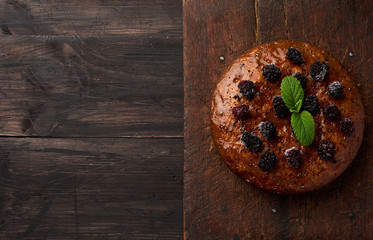 baked round biscuit cake with nuts and berries topped, wooden brown table