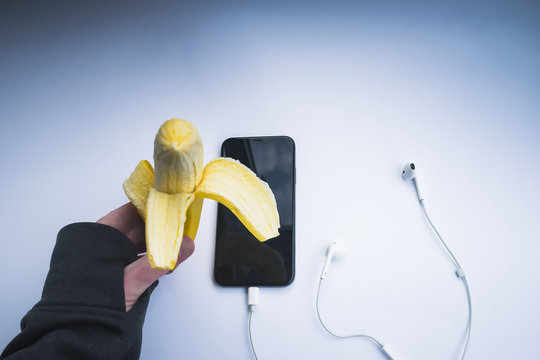 Man's Hand Eating A Banana Before Going For A Run With The Smartphone