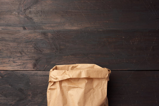 open brown paper bag for food packaging on a brown wooden background