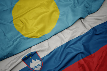 waving colorful flag of slovenia and national flag of Palau .