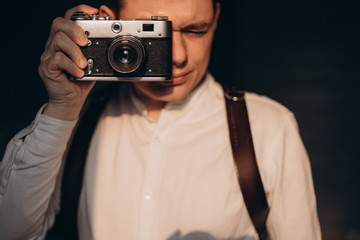 Fototapeta premium Portrait of a young men taking a photo with a vintage camera.