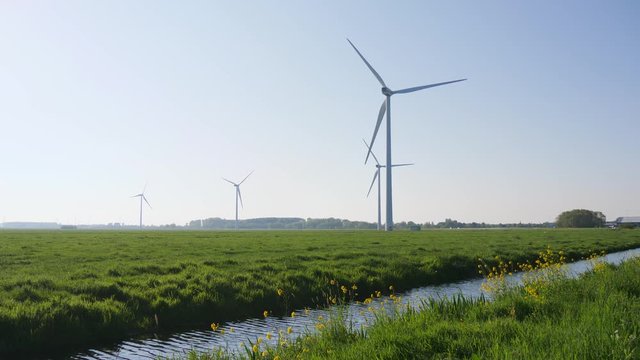 Wind turbines on a green pasture, road in background