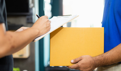 Delivery man sending parcel cardboard box to customer and signing receipt of delivery package.