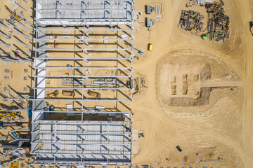 Construction site from above. Top view of factory under construction with heavy machinery. Picture made by drone from above.