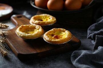 egg tarts on wooden board on dark background