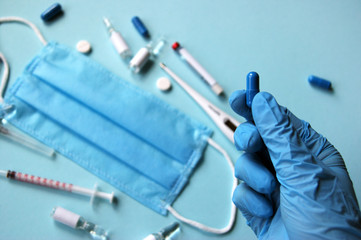 A female hand in gloves holds one blue pill.