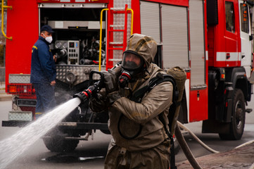 Obraz na płótnie Canvas The savior of the fire service disinfects the streets of the city. Preventive methods against coronavirus. Specialist in hazmat suits cleaning disinfecting coronavirus cells epidemic, pandemic health 