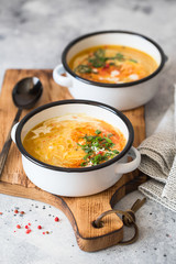 Pumpkin cream soup. Roasted pumpkin and carrot puree soup with turmeric, cream, paprica, chives and pumpkin seeds on grey background. Vegetarian and Vegan recipe. Green living. Organic food.