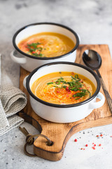 Pumpkin cream soup. Roasted pumpkin and carrot puree soup with turmeric, cream, paprica, chives and pumpkin seeds on grey background. Vegetarian and Vegan recipe. Green living. Organic food.