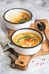 Pumpkin cream soup. Roasted pumpkin and carrot puree soup with turmeric, cream, paprica, chives and pumpkin seeds on grey background. Vegetarian and Vegan recipe. Green living. Organic food.