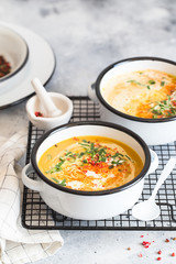 Pumpkin cream soup. Roasted pumpkin and carrot puree soup with turmeric, cream, paprica, chives and pumpkin seeds on grey background. Vegetarian and Vegan recipe. Green living. Organic food.