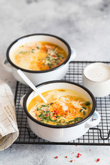 Pumpkin cream soup. Roasted pumpkin and carrot puree soup with turmeric, cream, paprica, chives and pumpkin seeds on grey background. Vegetarian and Vegan recipe. Green living. Organic food.