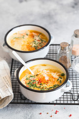 Pumpkin cream soup. Roasted pumpkin and carrot puree soup with turmeric, cream, paprica, chives and pumpkin seeds on grey background. Vegetarian and Vegan recipe. Green living. Organic food.