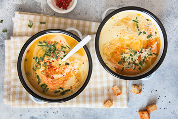 Pumpkin cream soup. Roasted pumpkin and carrot puree soup with turmeric, cream, paprica, chives and pumpkin seeds on grey background. Vegetarian and Vegan recipe. Green living. Organic food.