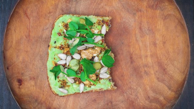 Avocado toast eating bite by bite. Loop stop motion animation. Healthy food vegan background. Natural wooden plate, top view.