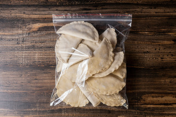 Frozen dumplings in batter in a plastic bag on a wooden background