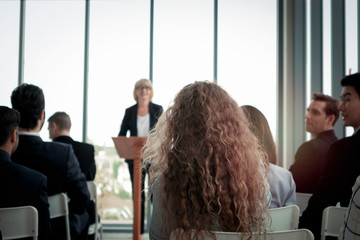 Group of business people sitting on conference together listening to the speaker giving a speech in...