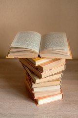 a stack of books on the table and one book is opened