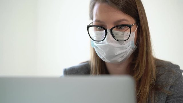 Young woman working at laptop computer in office mask during epidemic covid-19
