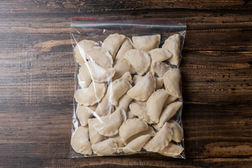 Frozen dumplings in batter in a plastic bag on a wooden background