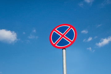 International traffic sign 'No parking' of 'No stopping'. Blue sky with small clouds is on background