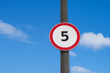 International traffic sign 'Speed limit' (to 5 km per hour) mounted on road post. Blue sky with little clouds are on  background