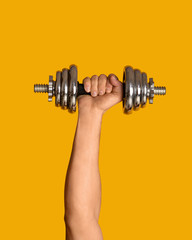 Plakat Close up of young bodybuilder holding dumbbell on orange background