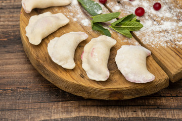 Frozen dumplings with cherry on a wooden plate on a wooden background