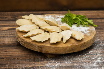 Frozen dumplings on a wooden plate on a wooden background