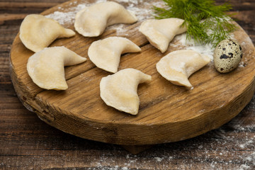 Frozen dumplings on a wooden plate on a wooden background