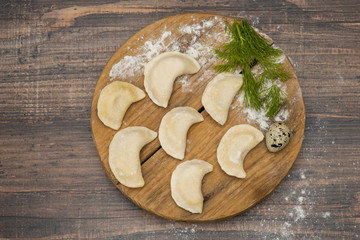 Fototapeta na wymiar Frozen dumplings on a wooden plate on a wooden background