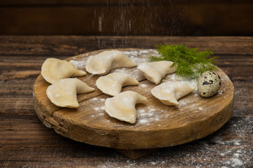 Frozen dumplings on a wooden plate on a wooden background